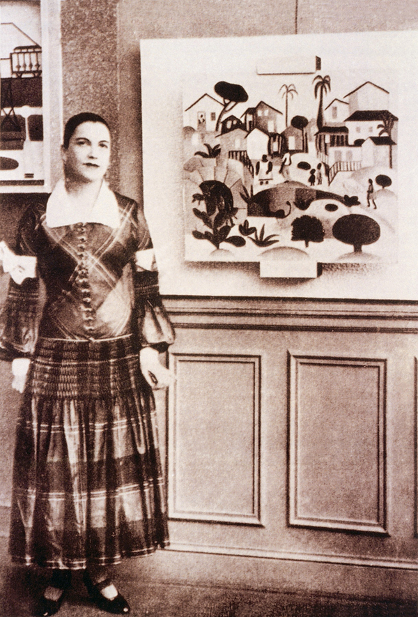 Tarsila do Amaral con vestido del costurero Paul Poiret posa junto a su obra “Morro de Favela” durante su exposición en París en 1926